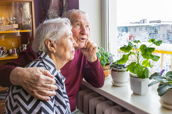 Two older people looking out a window. Courtesy of U of M School of Public Health to establish the Public Health Center of Excellence on Dementia Caregiving